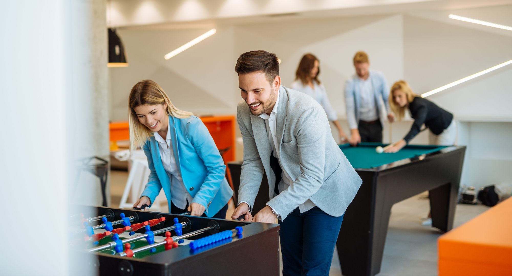 A man and a woman smiling and playing foosball