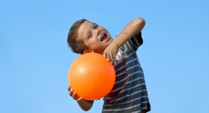 A boy smiling with an orange ball