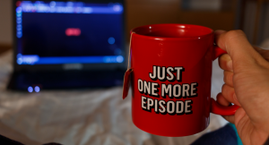 A person holding a mug that saying 'Just one more episode'